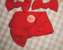 Red knitted headbands with a visible brand logo on a checkered background
